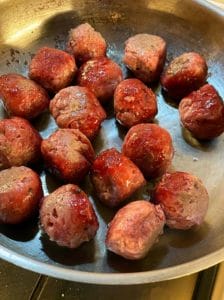 Harissa meatballs cooking in a frying pan