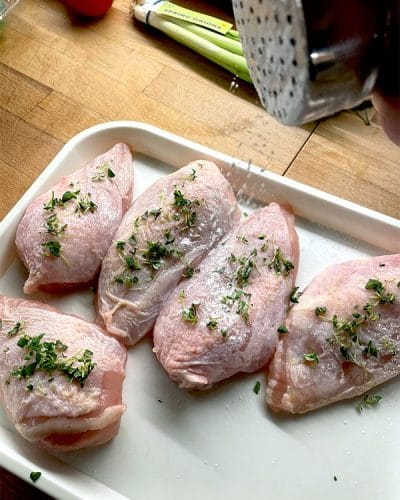 Seasoning chicken breasts with herbs