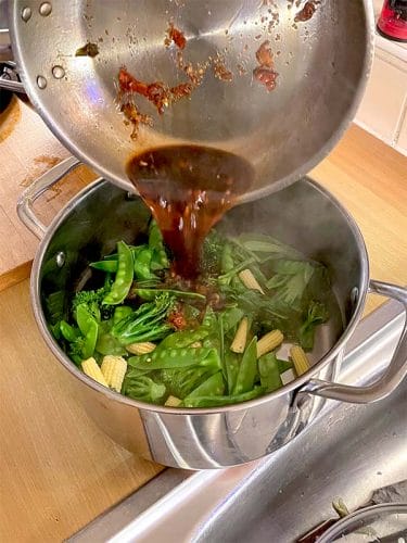 Pouring the dressing over the steamed vegetables